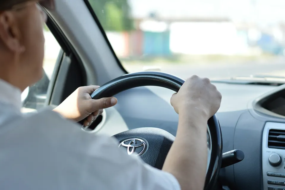 Hände am Lenkrad eines Autos während der Fahrt